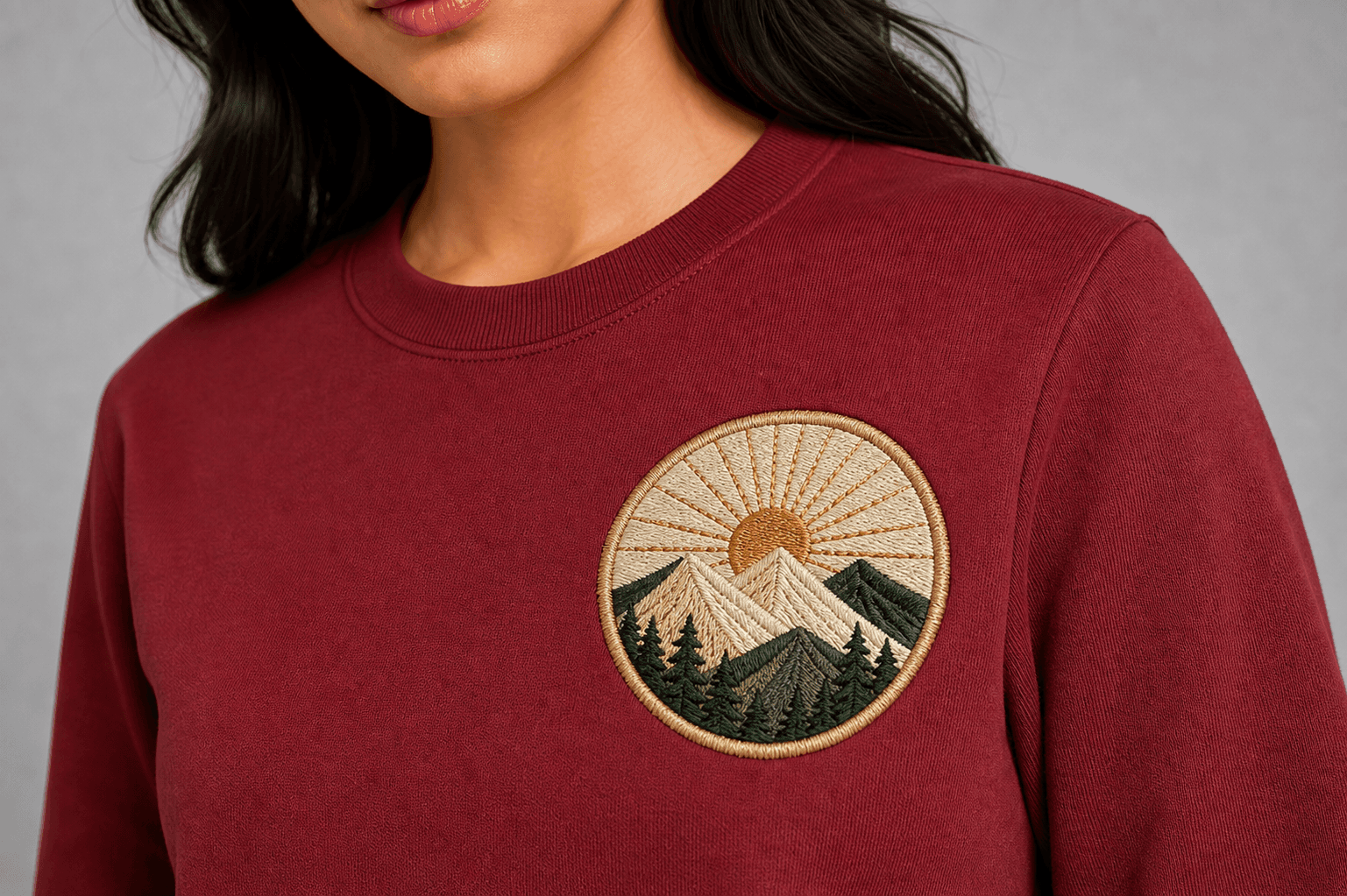 Detailed raised-thread mountain embroidery on a maroon sweatshirt